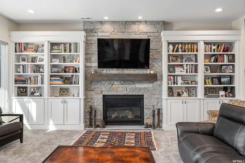 Living room featuring a fireplace, built in shelves, and carpet floors