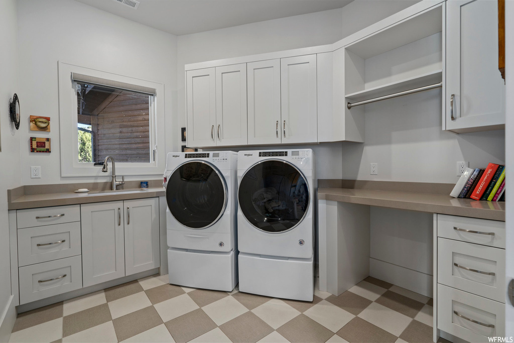 Laundry area featuring sink, separate washer and dryer, light tile floors, and cabinets