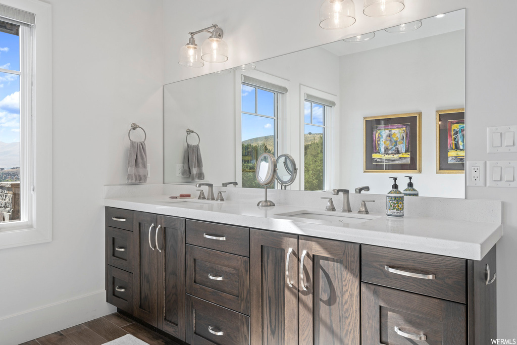 Bathroom with wood-type flooring, large vanity, dual sinks, and a wealth of natural light