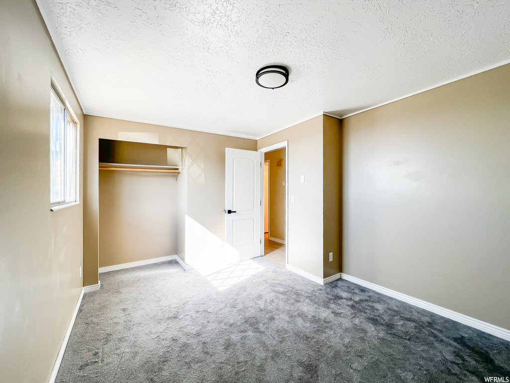 Unfurnished bedroom with light carpet, a textured ceiling, and a closet