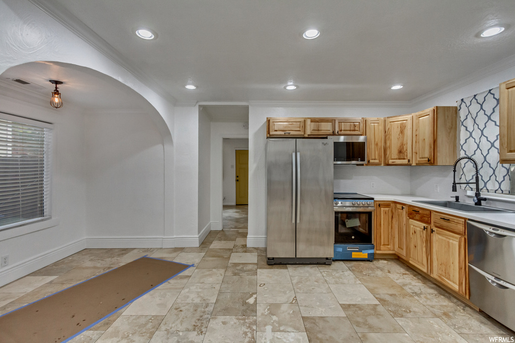 Kitchen featuring sink, light tile flooring, appliances with stainless steel finishes, and ornamental molding