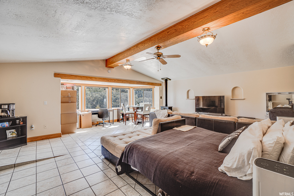 Tiled bedroom with a textured ceiling, ceiling fan, and lofted ceiling with beams