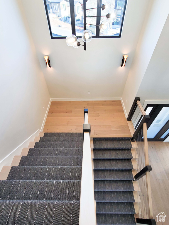Staircase with dark hardwood / wood-style flooring and an inviting chandelier
