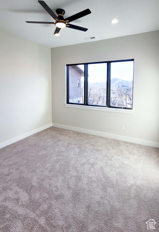 Spare room with a mountain view, light colored carpet, and ceiling fan