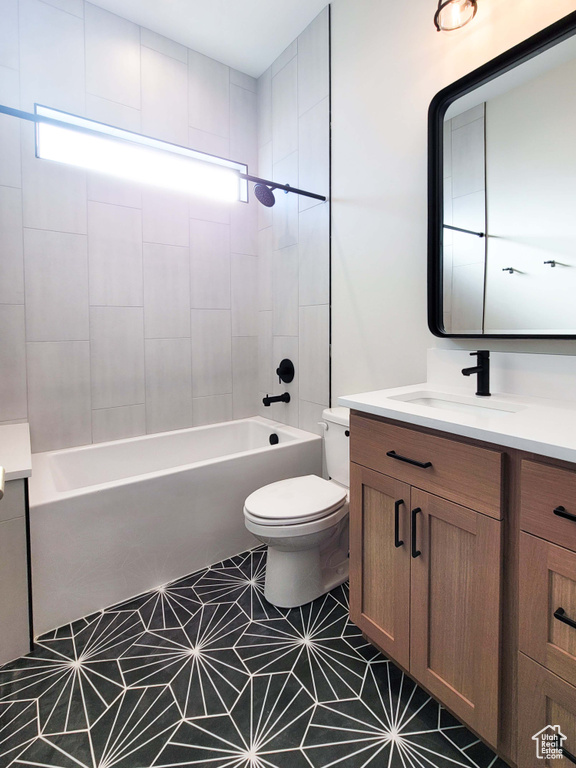 Full bathroom featuring tile floors, vanity, toilet, and tiled shower / bath
