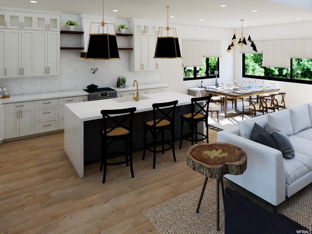 Kitchen featuring a kitchen island with sink, white cabinets, and decorative light fixtures