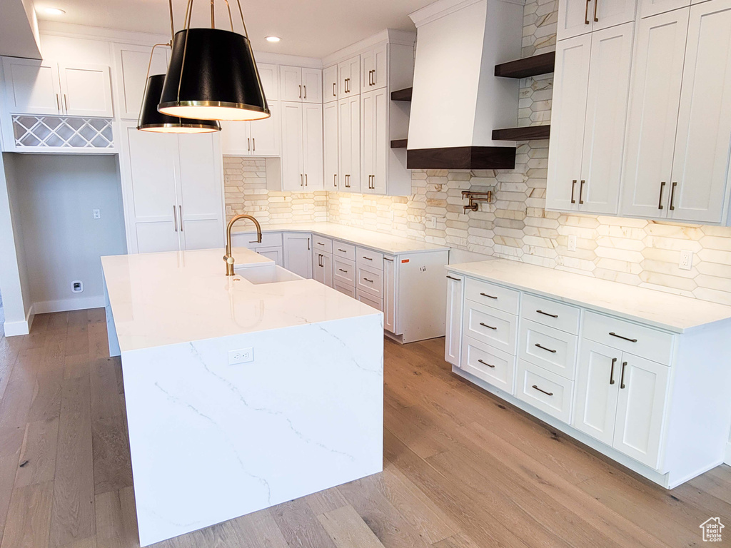 Kitchen featuring tasteful backsplash, light hardwood / wood-style floors, decorative light fixtures, and sink