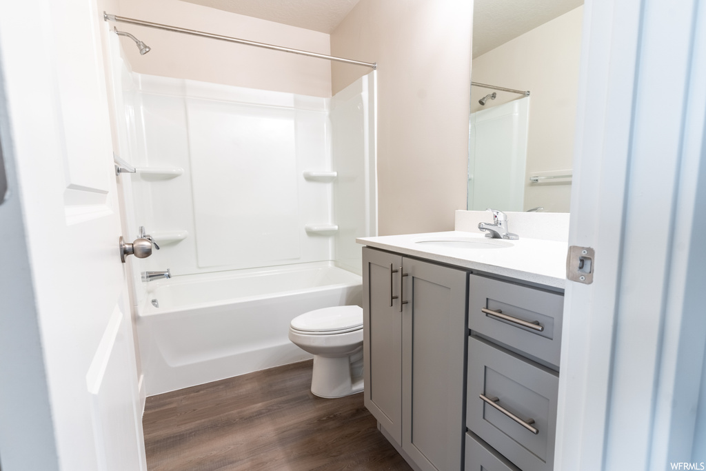 Full bathroom with vanity with extensive cabinet space, toilet, washtub / shower combination, and hardwood floors