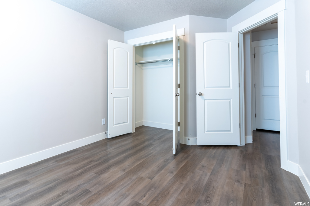 Unfurnished bedroom with dark hardwood flooring and a closet