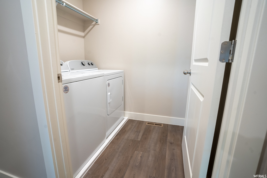 Washroom with independent washer and dryer and dark hardwood flooring