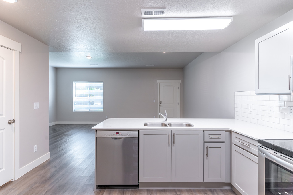 Kitchen featuring kitchen peninsula, dishwasher, sink, and dark hardwood flooring