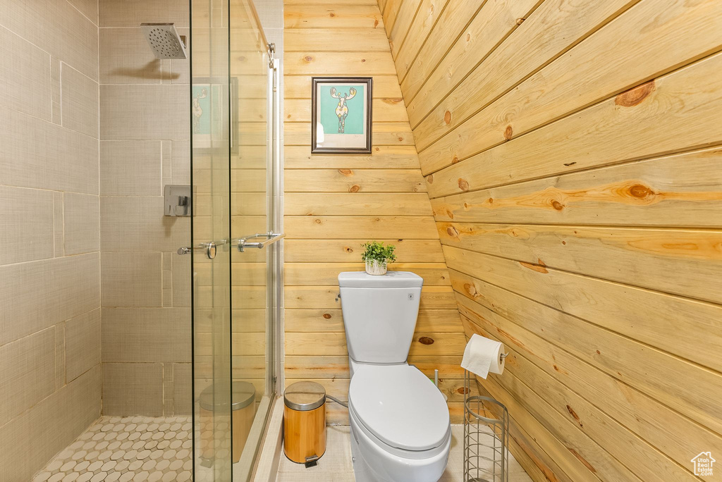 Bathroom featuring walk in shower, wooden walls, and toilet