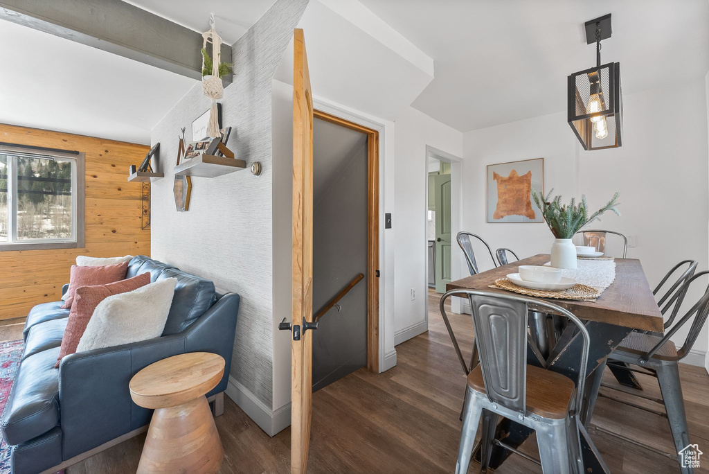 Dining room with dark hardwood / wood-style flooring and wood walls