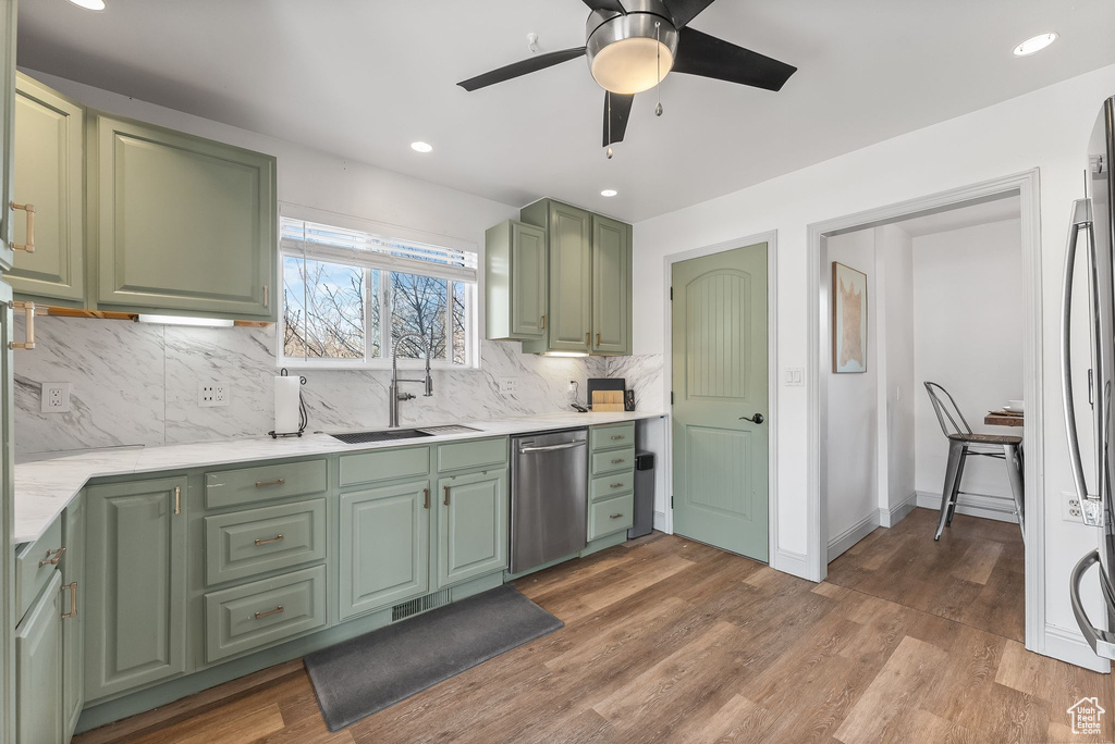 Kitchen featuring green cabinets, appliances with stainless steel finishes, hardwood / wood-style flooring, tasteful backsplash, and ceiling fan