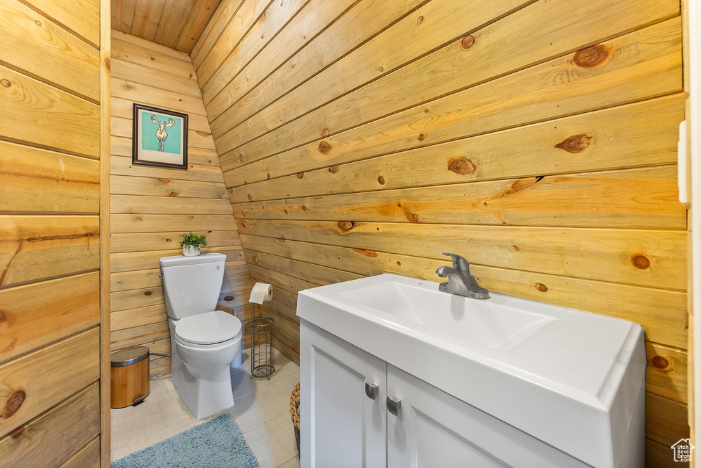 Bathroom with wood walls, toilet, tile flooring, vanity, and wood ceiling