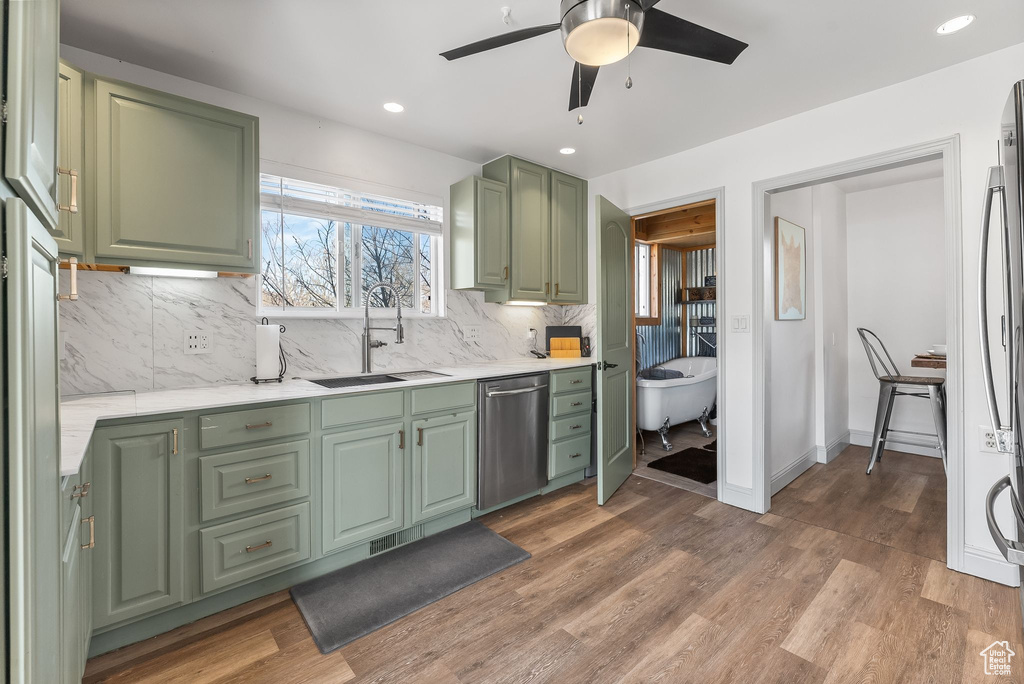 Kitchen featuring ceiling fan, dishwasher, tasteful backsplash, hardwood / wood-style flooring, and green cabinets