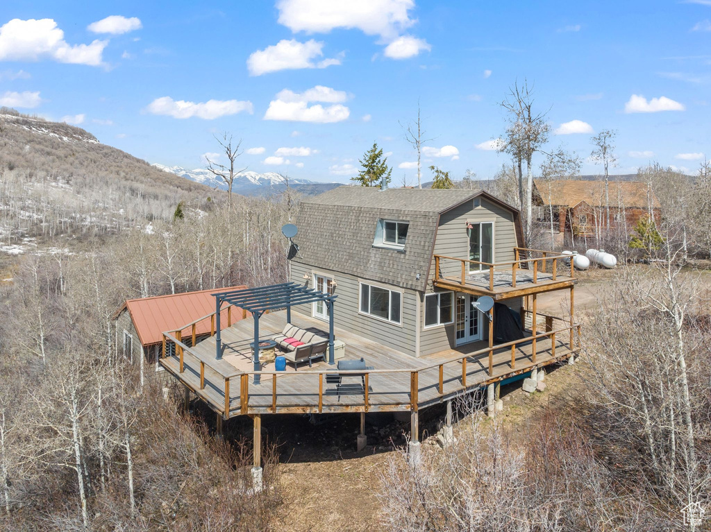 Back of house with an outdoor living space and a deck with mountain view