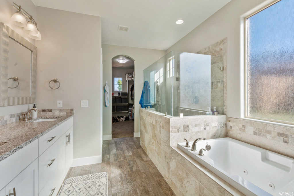 Bathroom with plenty of natural light, hardwood flooring, vanity, and plus walk in shower