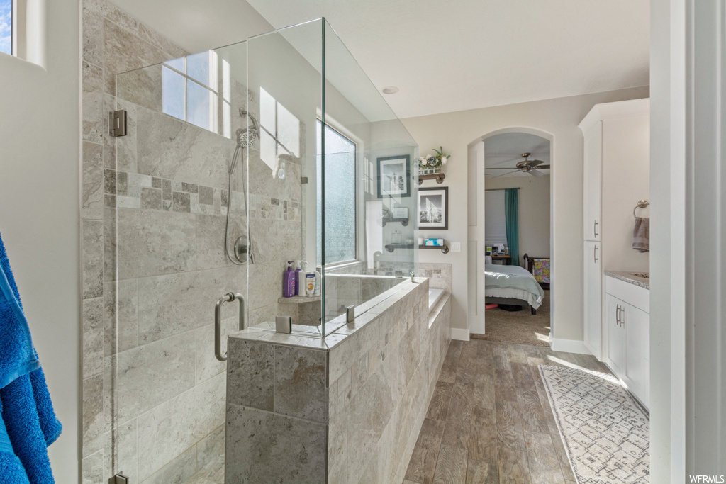 Bathroom featuring hardwood flooring, vanity, shower with separate bathtub, and ceiling fan