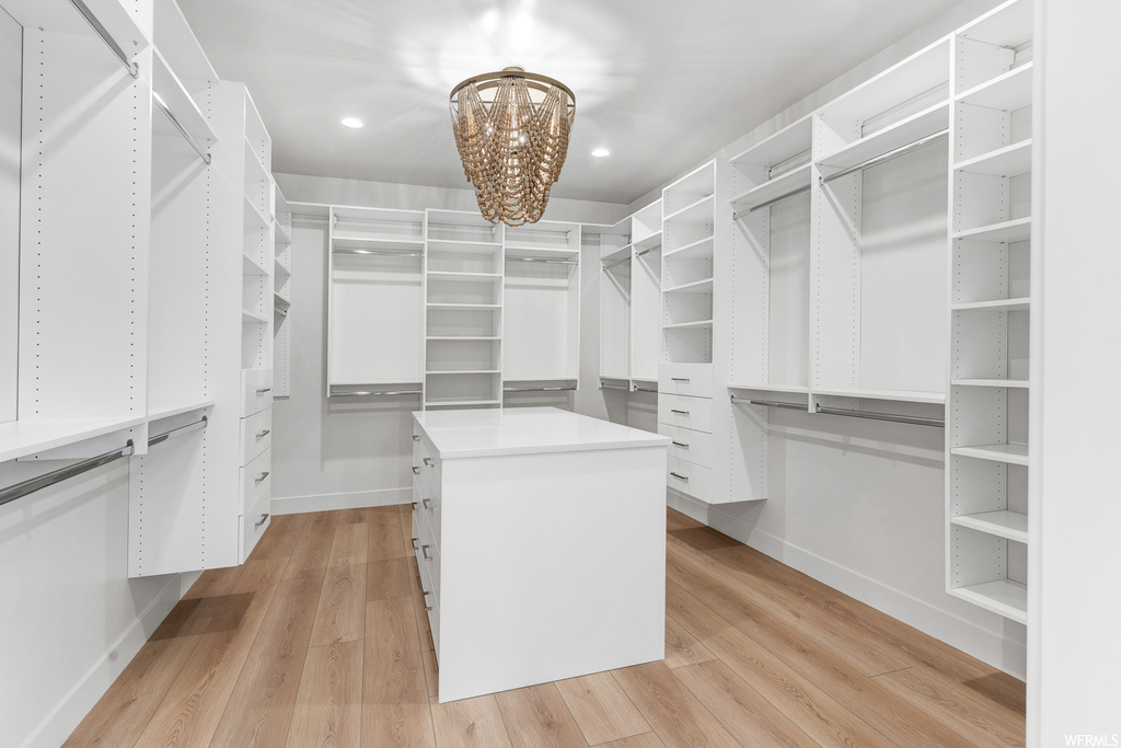 Walk in closet with a notable chandelier and light hardwood floors
