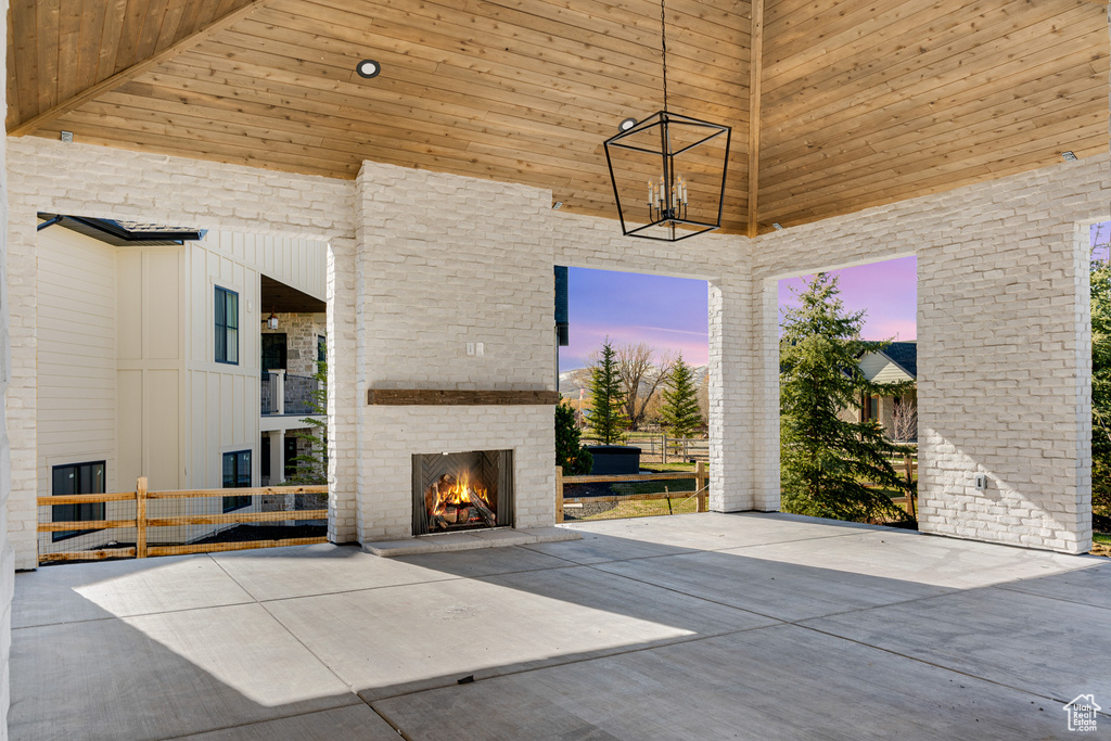 Exterior space featuring wood ceiling, brick wall, and an outdoor brick fireplace