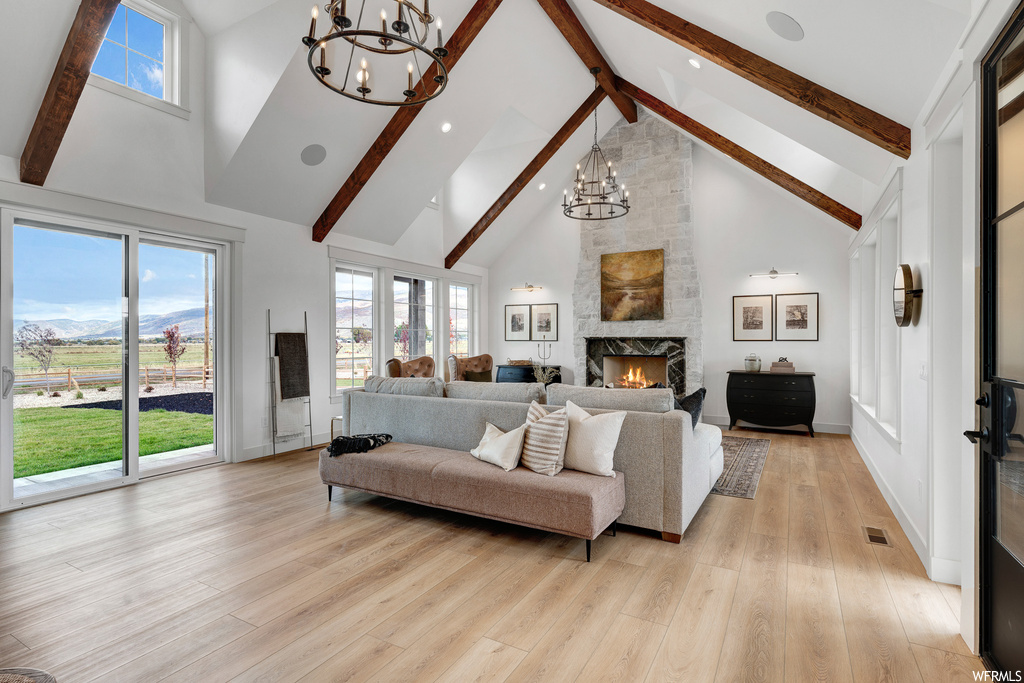 Living room with an inviting chandelier, vaulted ceiling high, light hardwood floors, and a fireplace