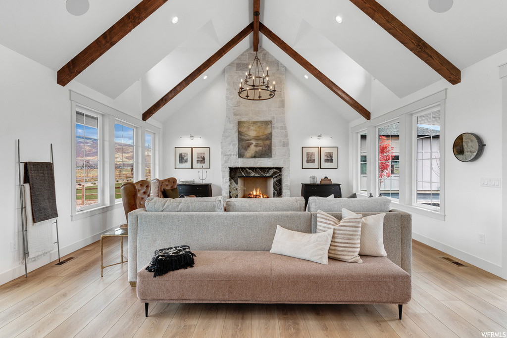 Living room featuring vaulted ceiling high, an inviting chandelier, a fireplace, and light hardwood flooring