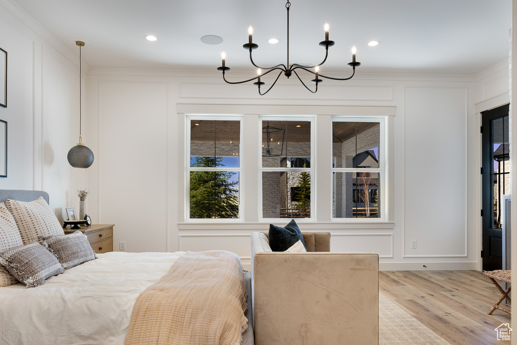 Bedroom featuring ornamental molding, a notable chandelier, and light hardwood / wood-style flooring