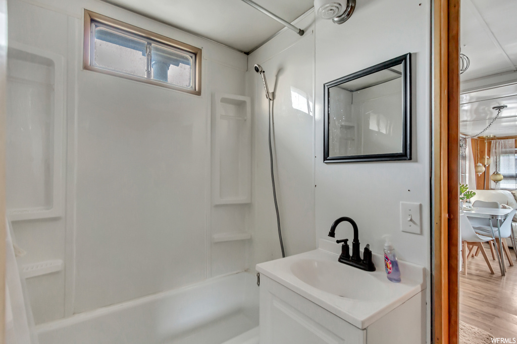 Bathroom with vanity, hardwood / wood-style flooring, and tub / shower combination