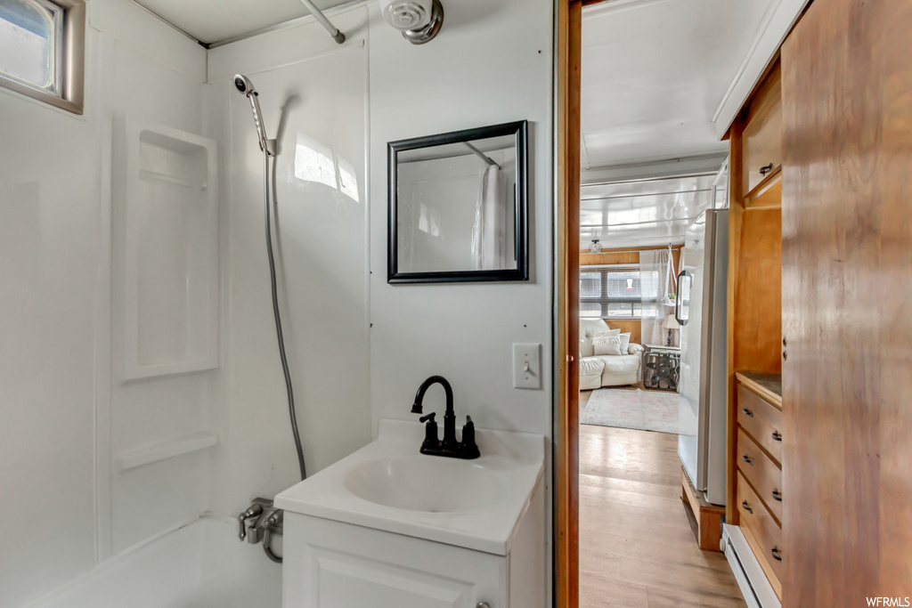 Bathroom featuring oversized vanity, hardwood / wood-style floors, and washtub / shower combination