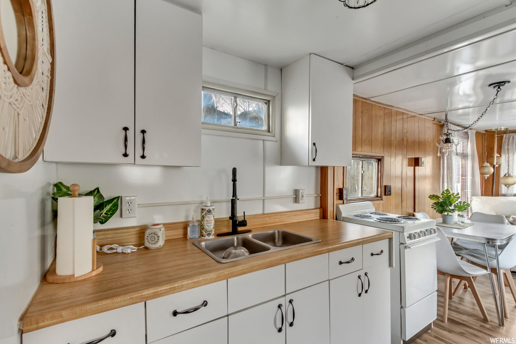 Kitchen featuring white gas stove, light hardwood / wood-style flooring, and white cabinetry