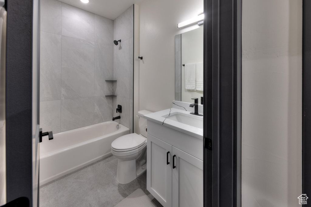 Full bathroom featuring tile floors, tiled shower / bath combo, oversized vanity, and toilet