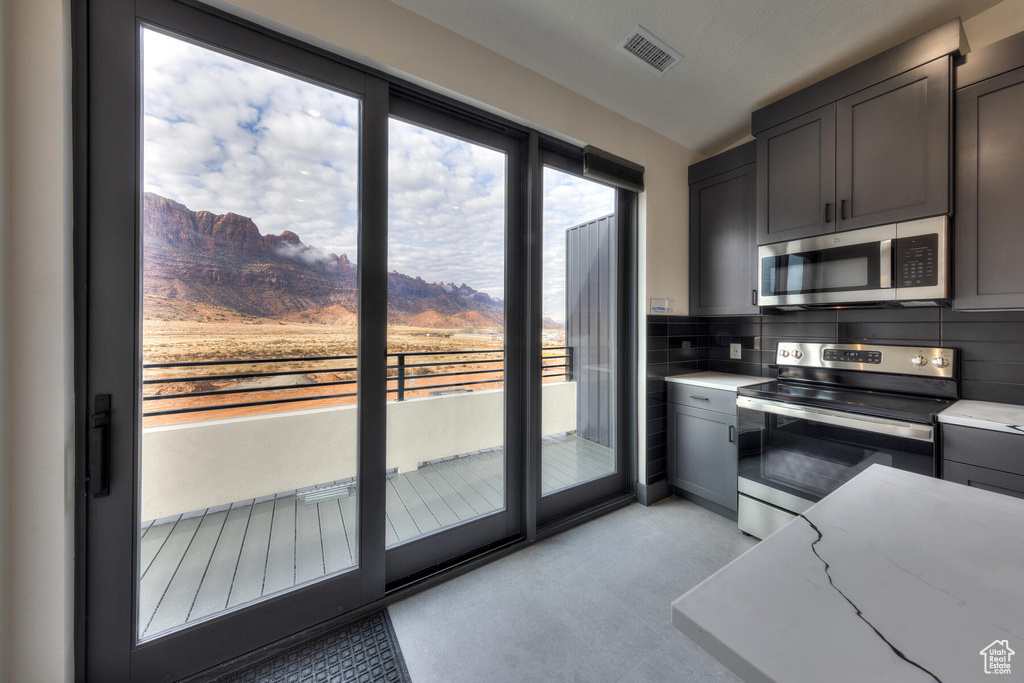 Kitchen with a mountain view, appliances with stainless steel finishes, light stone counters, and backsplash