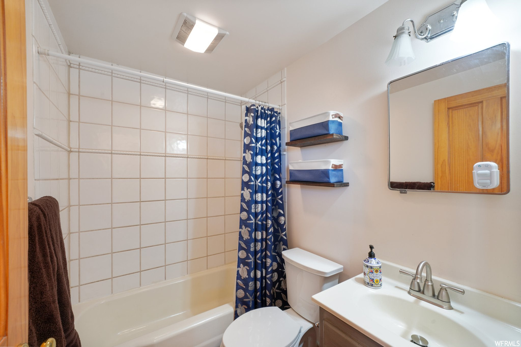 Full bathroom with toilet, vanity, and shower / bathtub combination with curtain
