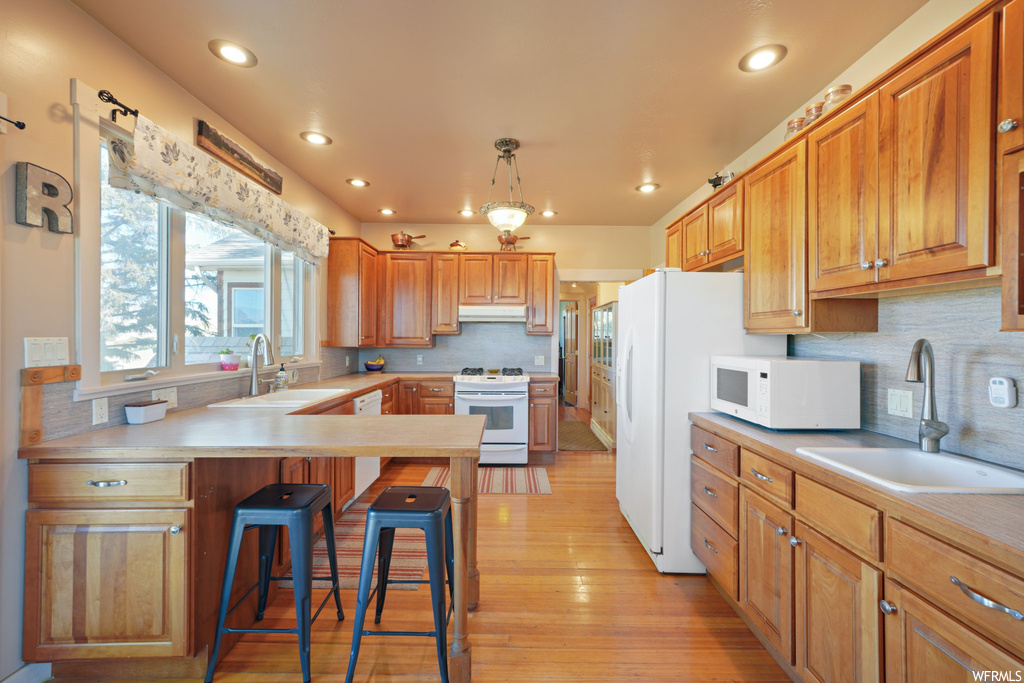 Kitchen with sink, pendant lighting, light hardwood floors, and tasteful backsplash