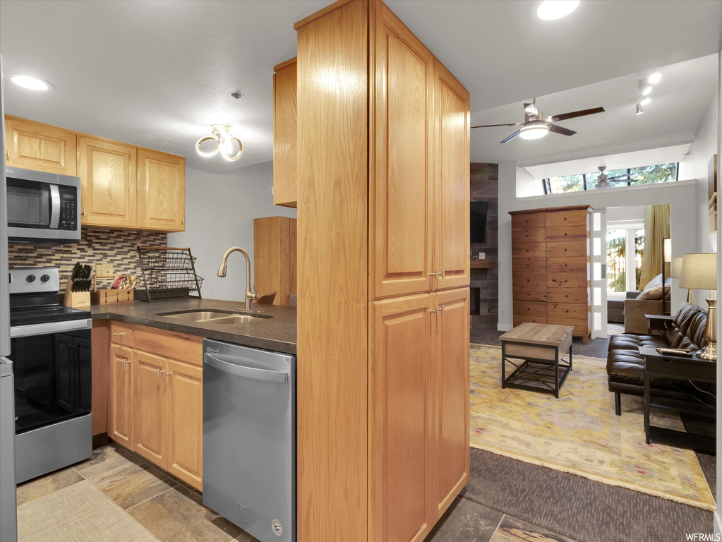 Kitchen featuring ceiling fan, light tile floors, backsplash, stainless steel appliances, and sink
