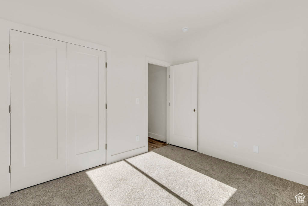 Unfurnished bedroom with light carpet and a closet