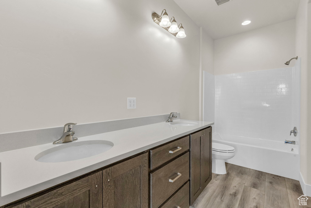 Full bathroom featuring dual vanity, wood-type flooring, shower / tub combination, and toilet