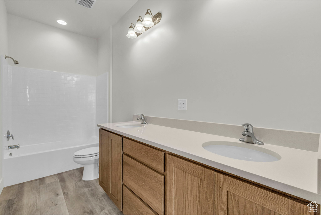 Full bathroom featuring shower / washtub combination, toilet, hardwood / wood-style floors, and dual bowl vanity