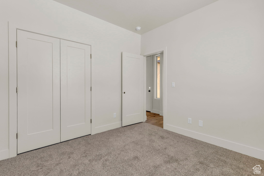 Unfurnished bedroom with light colored carpet and a closet