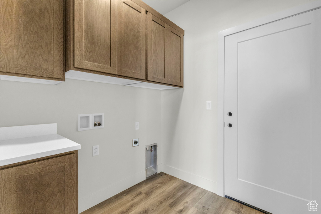 Laundry room with hookup for a washing machine, light hardwood / wood-style flooring, hookup for an electric dryer, and cabinets