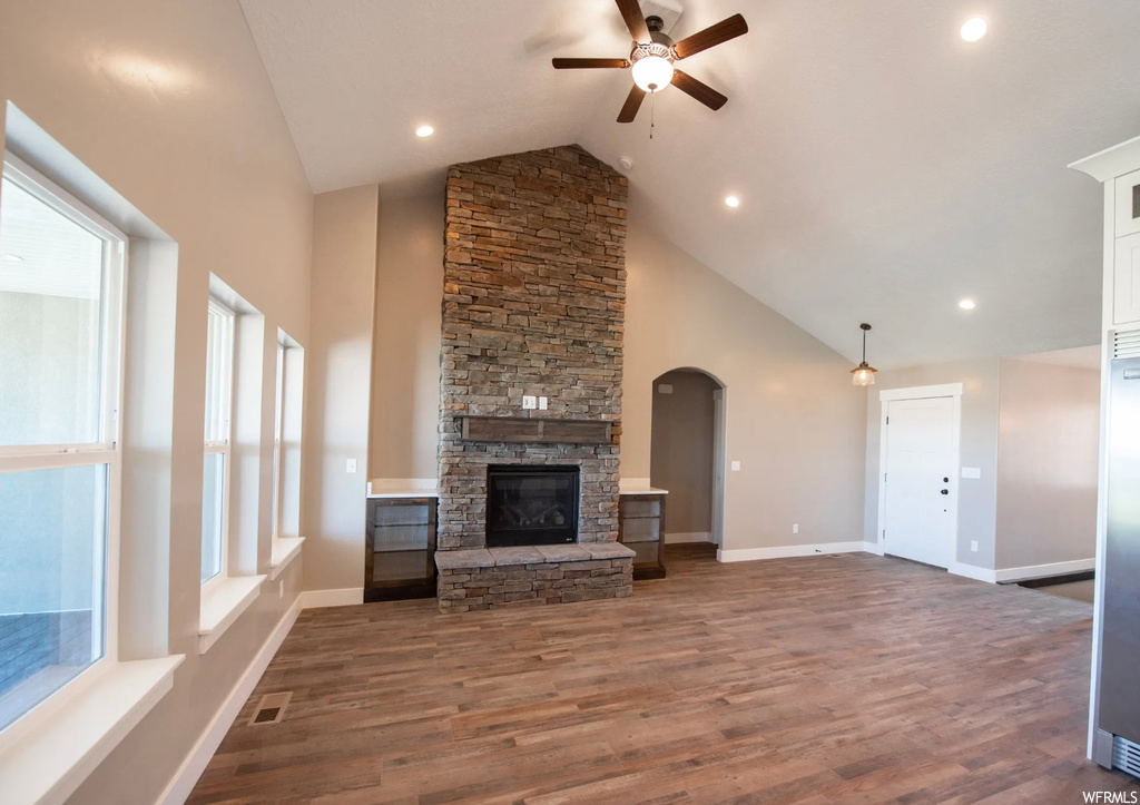 Unfurnished living room featuring a fireplace, ceiling fan, vaulted ceiling high, and dark hardwood flooring