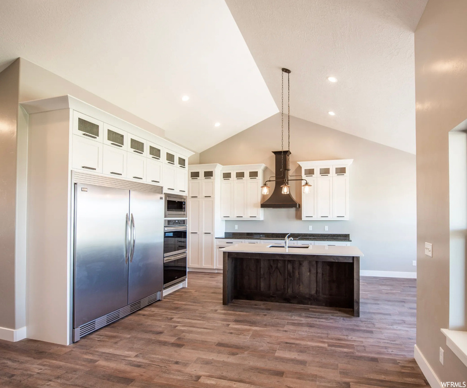 Kitchen featuring sink, dark hardwood flooring, premium range hood, built in appliances, and decorative light fixtures