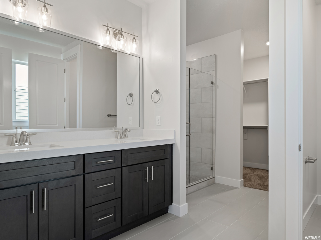 Bathroom with an enclosed shower, double vanity, and tile flooring