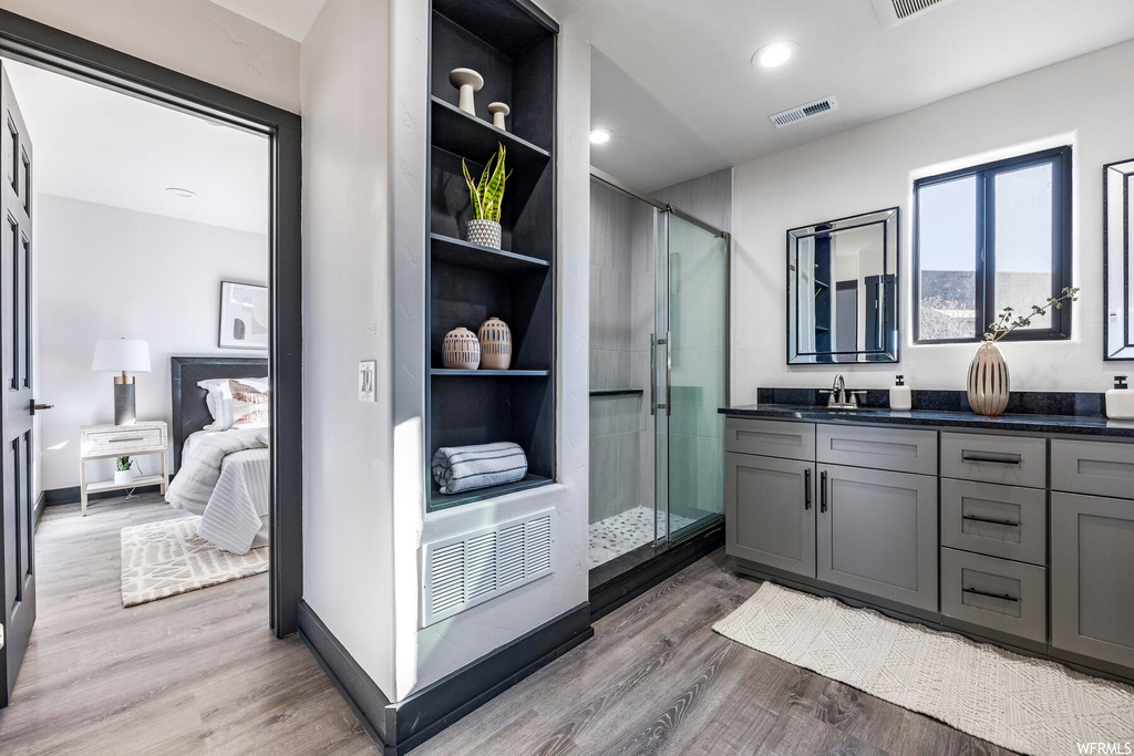 Bathroom featuring a shower with door, wood-type flooring, and vanity with extensive cabinet space