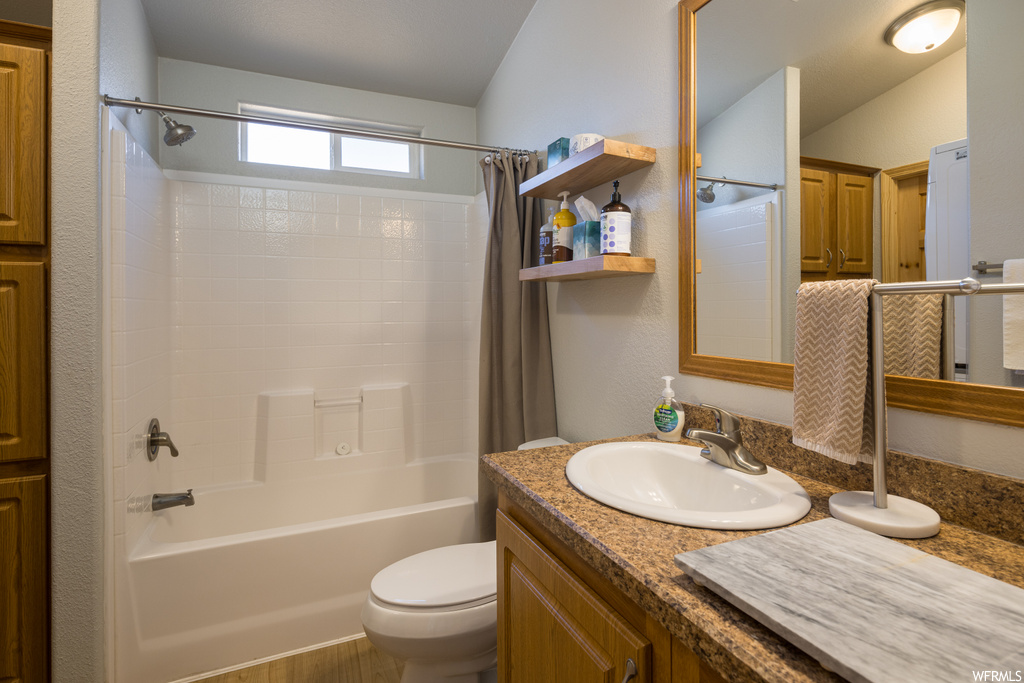 Full bathroom featuring shower / bath combination with curtain, toilet, and vanity with extensive cabinet space