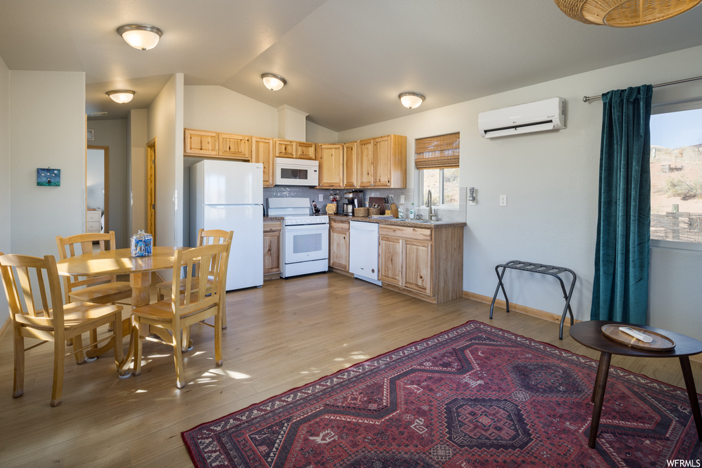 Kitchen with lofted ceiling, a wall unit AC, tasteful backsplash, white appliances, and light hardwood / wood-style flooring
