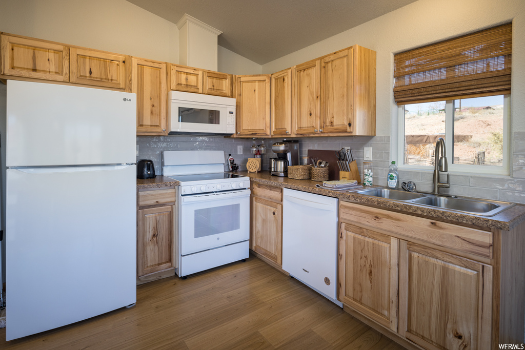 Kitchen featuring lofted ceiling, white appliances, sink, and tasteful backsplash