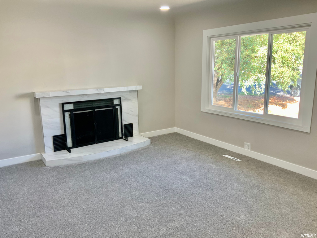 Unfurnished living room with carpet floors and a fireplace