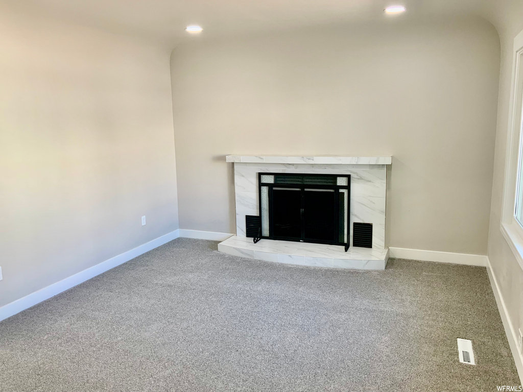 Unfurnished living room with light carpet and a fireplace